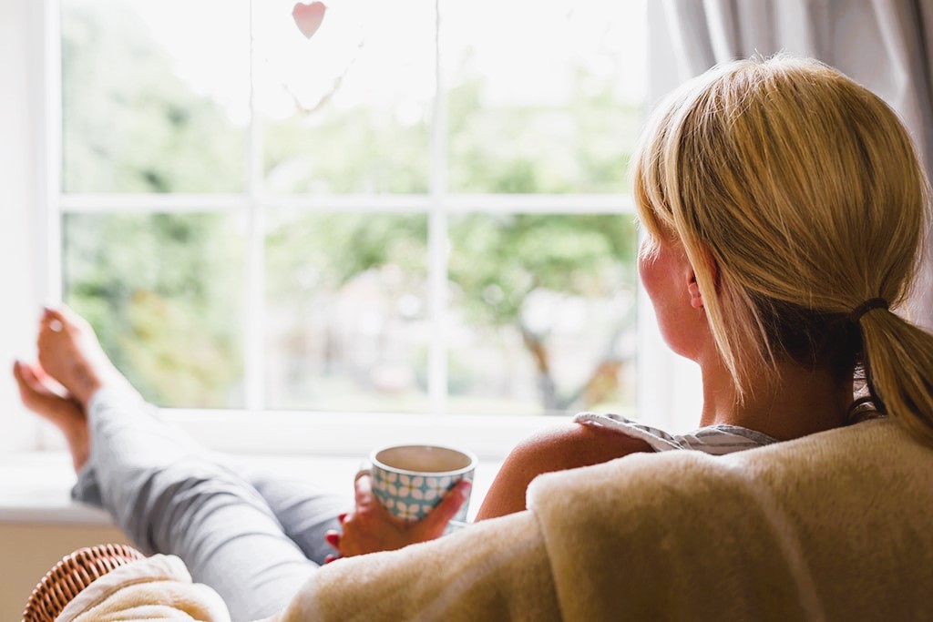Girl with a cup of coffee admiring the new window